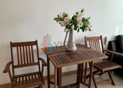 Living area with wooden table, chairs, and vase with flowers