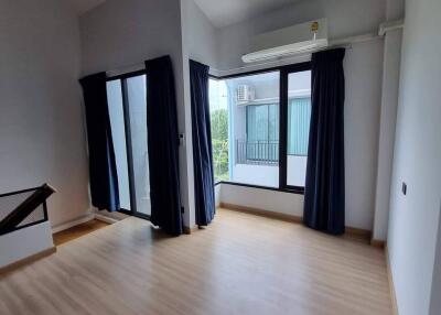 Spacious bedroom with wooden flooring and large windows