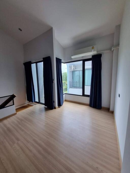 Spacious bedroom with wooden flooring and large windows