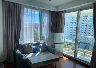 Living room with sofa, coffee table, refrigerator, and balcony view