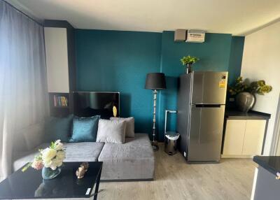 Living room with teal accent wall, seating area, and refrigerator