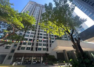 Exterior view of a high-rise residential building with trees and greenery