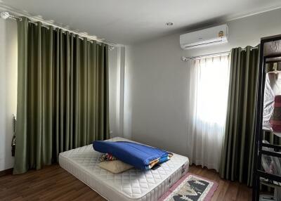 Simple bedroom with mattress, green curtains, and a small rug