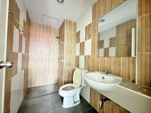 Modern bathroom with tiled walls, a shower, toilet, and sink