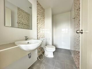 Modern bathroom with sink, toilet, and tiled walls