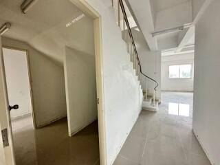 Spacious white-walled room with staircase and open hallway