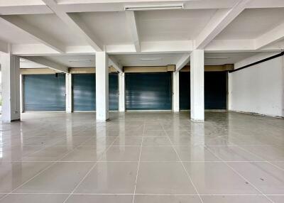 Spacious commercial area with tiled flooring and roller shutter doors