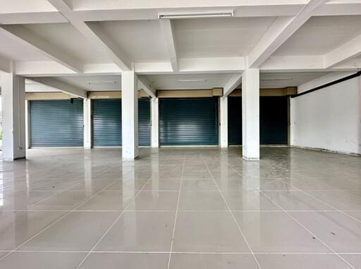 Spacious commercial area with tiled flooring and roller shutter doors