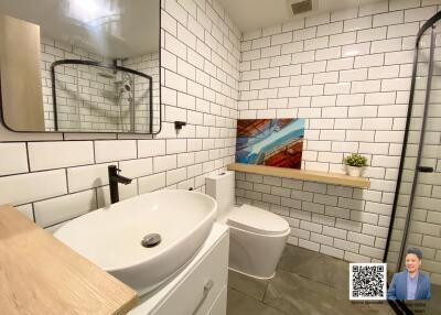 Modern bathroom with white subway tiles, a round vessel sink, and a wall-mounted mirror