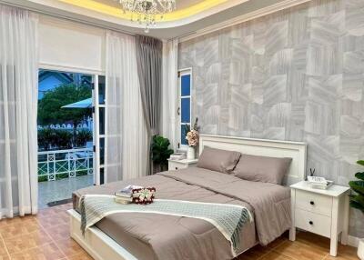 Spacious bedroom with double bed, bedside tables, and large windows leading to an outdoor area