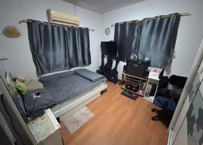 Bedroom with wooden flooring, a bed, and a small workspace