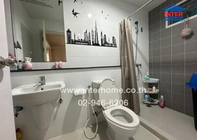 Modern bathroom with wall decorations, including a sink, toilet, and shower area