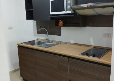 Modern kitchen with wooden cabinets, sink, and microwave