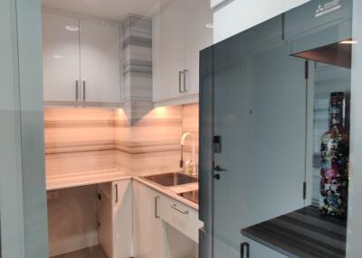 Modern compact kitchen area with white cabinetry and built-in appliances