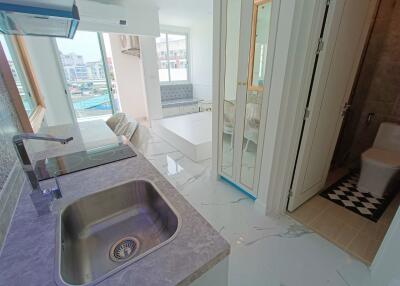 Modern kitchen area with a view of living space and bathroom