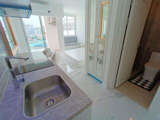 Modern kitchen area with a view of living space and bathroom