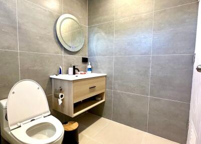 Modern bathroom with circular mirror and floating vanity.