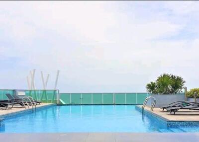 Rooftop swimming pool with lounge chairs and ocean view