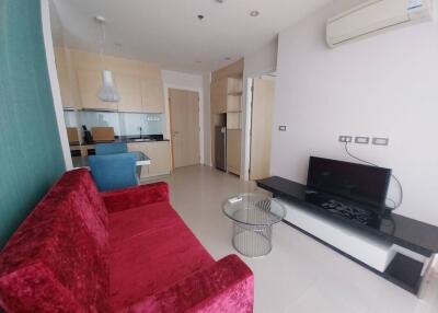 Modern living room with a red couch, glass coffee table, TV, and dining area