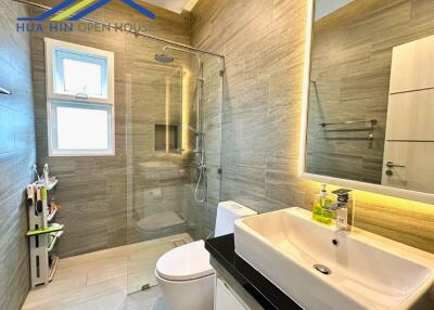 Modern bathroom with a glass shower enclosure, wall-mounted sink, and toilet