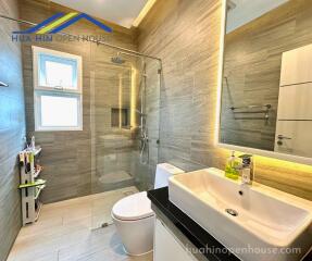 Modern bathroom with a glass shower enclosure, wall-mounted sink, and toilet