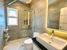 Modern bathroom with a glass shower enclosure, wall-mounted sink, and toilet