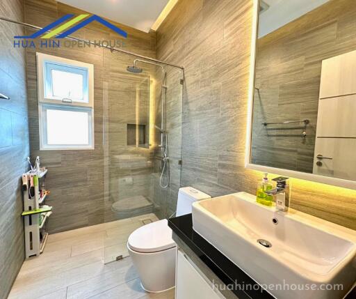 Modern bathroom with a glass shower enclosure, wall-mounted sink, and toilet