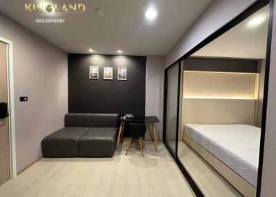 Modern living area with adjoining bedroom featuring a sofa, desk, and large mirrored closet