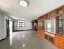 Spacious living room with built-in wooden cabinets and large windows