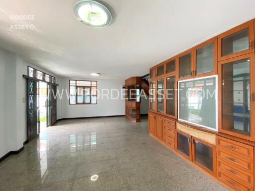 Spacious living room with built-in wooden cabinets and large windows