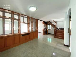 Spacious living area with wooden built-in cabinet and staircase