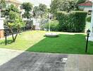 spacious backyard with green lawn and paved area