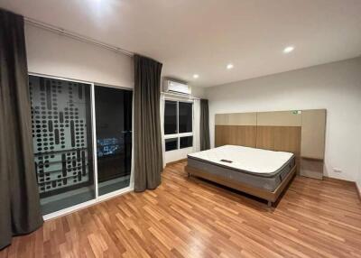 Spacious bedroom with wooden floor and large bed next to windows.