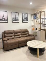 Modern living room with brown leather sofa and framed city prints