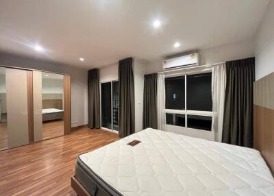 Spacious bedroom with hardwood floors, a large window, and a bed.