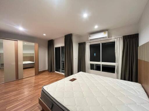 Spacious bedroom with hardwood floors, a large window, and a bed.