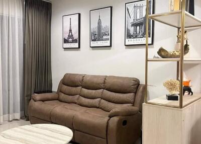 Modern living room with comfortable brown sofa, wall art, and open shelving