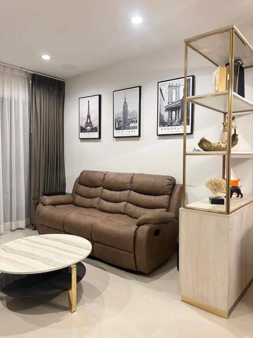 Modern living room with comfortable brown sofa, wall art, and open shelving