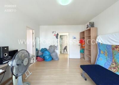 Spacious bedroom with wooden flooring, shelves, and a fan