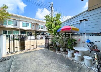 Front yard with a gate, plants, seating area, and neighboring houses