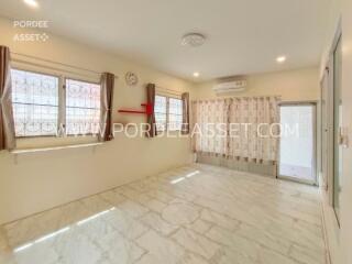 Bright living room with large windows, air conditioning, and tiled floors.