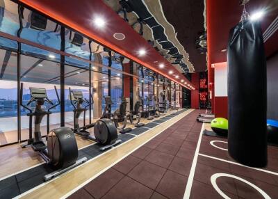 Modern gym with various fitness equipment and evening city view