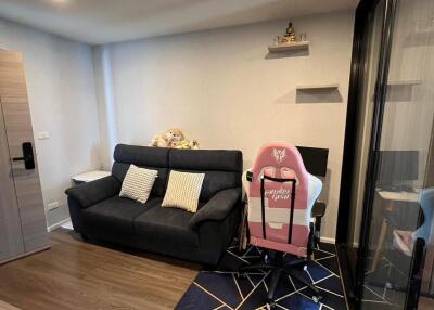 Living room with sofa, desk chair, shelf, and modern decor