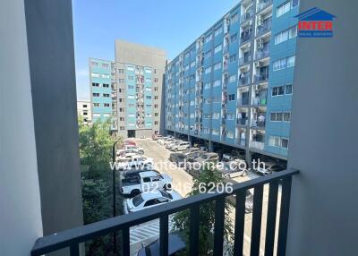 View from a balcony overlooking a parking lot and multiple apartment buildings