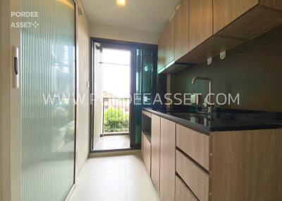 Modern kitchen area with wooden cabinetry and access to outdoor space