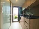 Modern kitchen area with wooden cabinetry and access to outdoor space