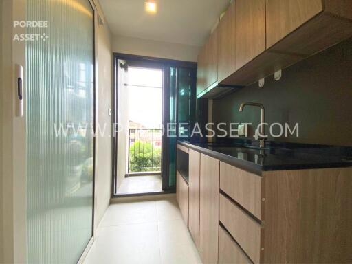 Modern kitchen area with wooden cabinetry and access to outdoor space