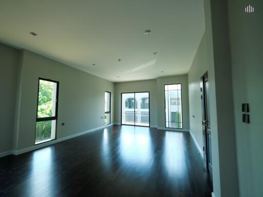 Bright and spacious main living area with large windows and dark hardwood floors