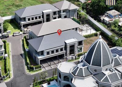 Aerial view of a modern residential complex with a central domed building and multiple two-story houses