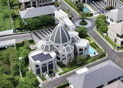 Aerial view of a modern residential building with a distinctive dome and solar panels on the roof